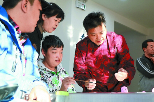 兔儿爷第五代传人张忠强（右一）正向马钢（左一）等残疾人教授彩塑技艺。