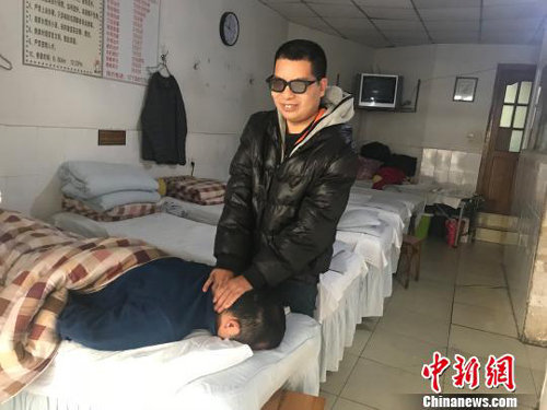 黄训忠在按摩店为顾客提供推拿按摩服务。魏尧摄