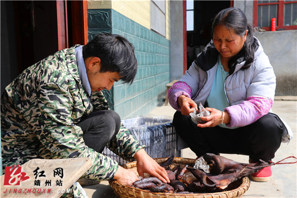 黄水林正蹲着和妈妈一起仔细地将腊肠和血丸子打包装袋。易子明 摄